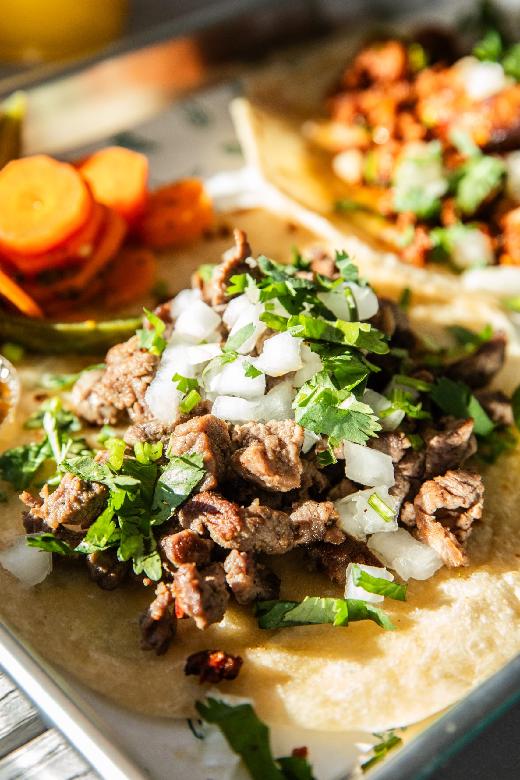 Close-up of beef taco topped with diced onions and cilantro on a warm tortilla.